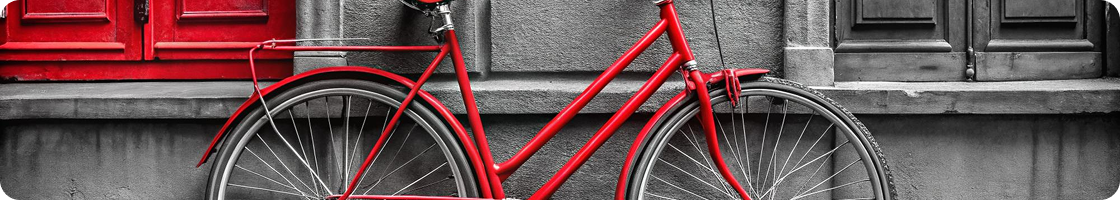 Red city bicycle parked against a wall